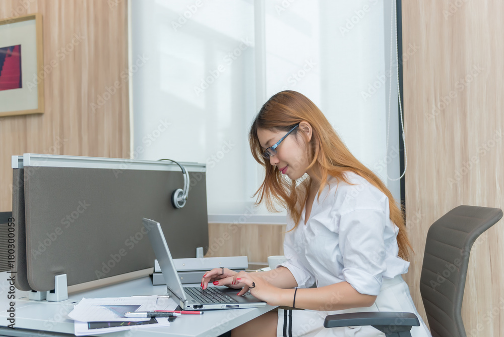 Thai girl work on the desk,businesswoman in white dress working at the company Thai girl work on the desk,businesswoman in white dress working at the company