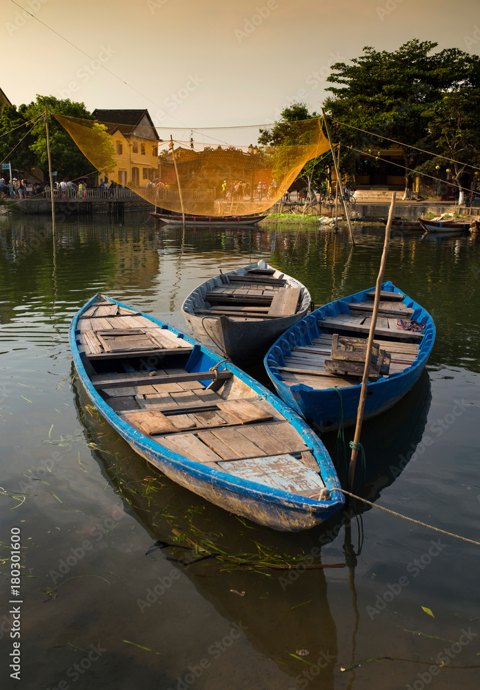 Fototapeta premium Wooden boats on the Thu Bon river in Hoi An ancient town at sunset time. Hoi An is a UNESCO world heritage site in Vietnam