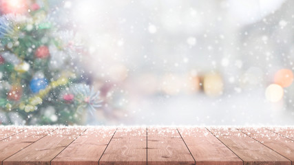 Wood table top on blur with bokeh christmas tree background with snowfall - can be used for display or montage your products.