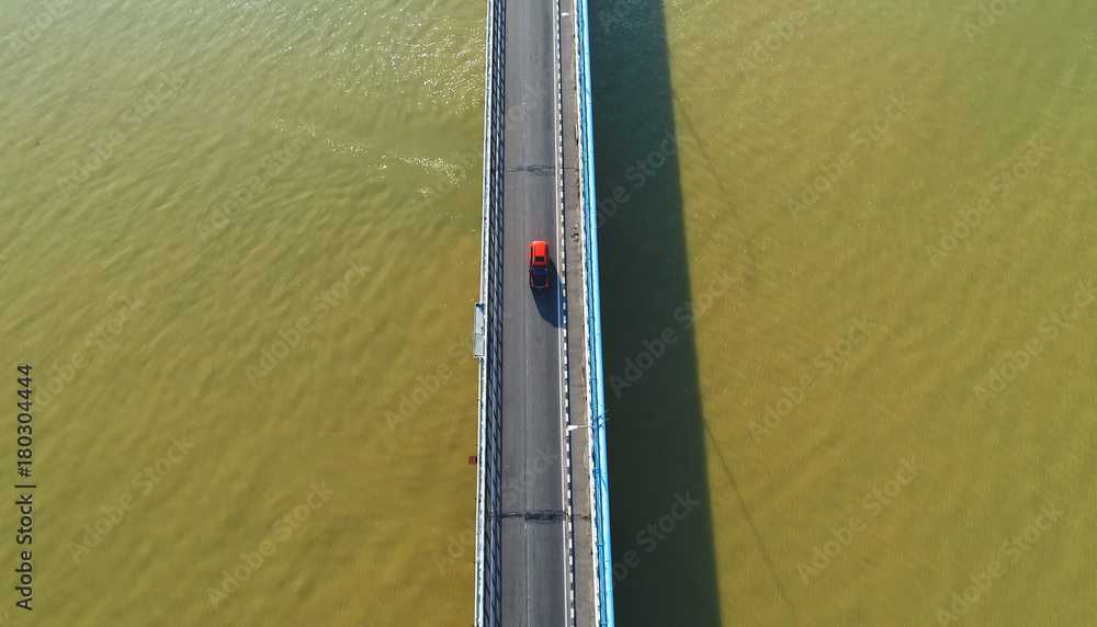 Obraz premium Aerial view. A red car on a bridge.