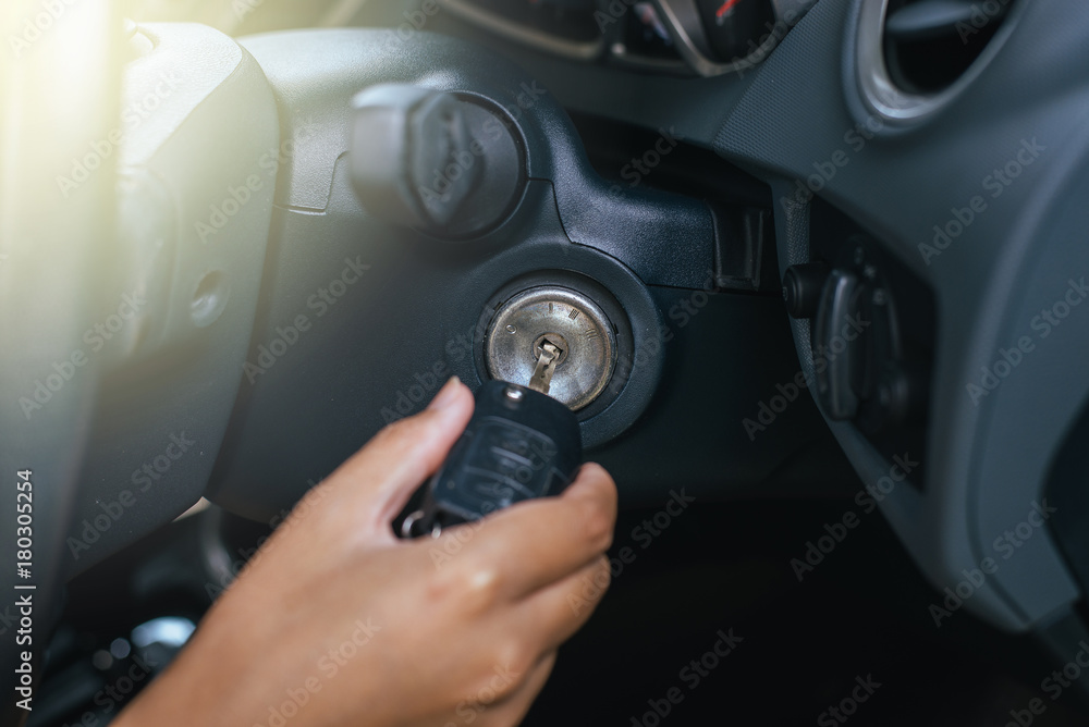 Hand of woman inserting key to start car system,Button on dashboard in car panel