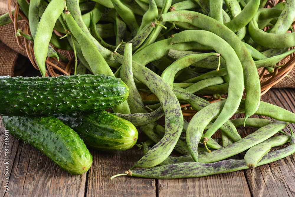 Green beans pods, cucumbers on wooden surface Green beans pods, cucumbers on wooden surface