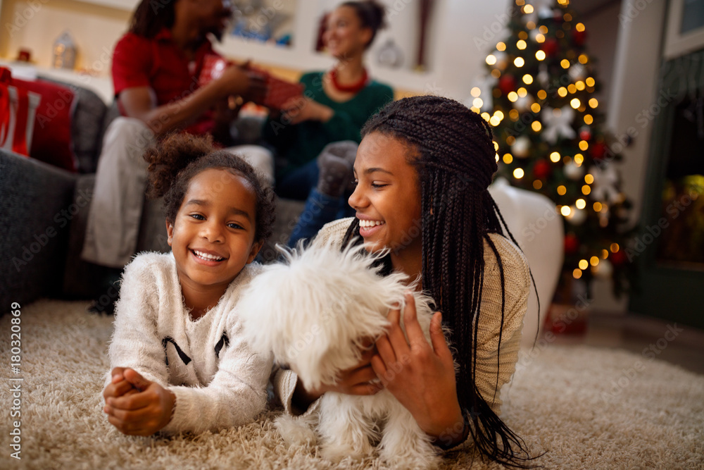 little sisters are playing with dog and laughing. They are lying on floor near Christmas tree. little sisters are playing with dog and laughing. They are lying on floor near Christmas tree.
