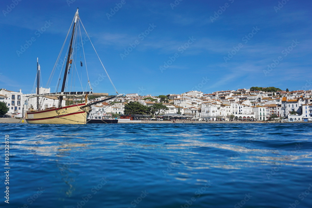 Spain a traditional boat and the village of Cadaques on the shore of the Mediterranean sea, seen from water surface, Costa Brava, Catalonia