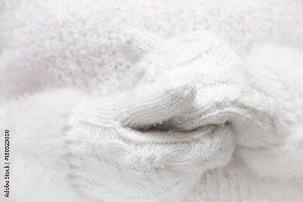 White, soft knitted womanly mittens on fluffy sweater background. Winter time wear concept. White, soft knitted womanly mittens on fluffy sweater background. Winter time wear concept.