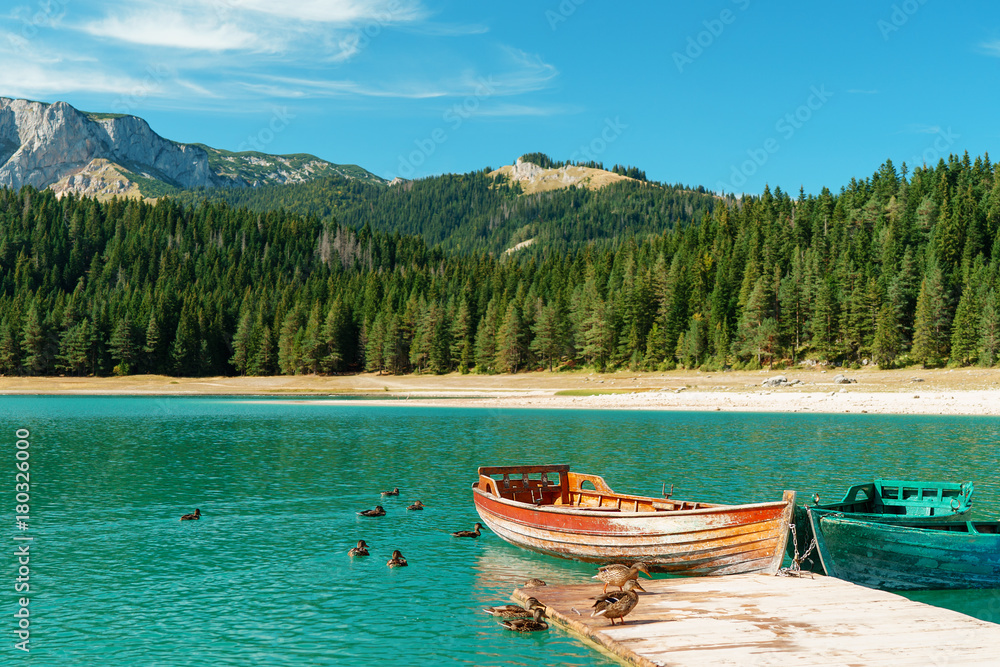 Stunning romantic place with typical wooden boats on the lake pier. Black Lake, Durmitor, Montenegro. Stunning romantic place with typical wooden boats on the lake pier. Black Lake, Durmitor, Montenegro.