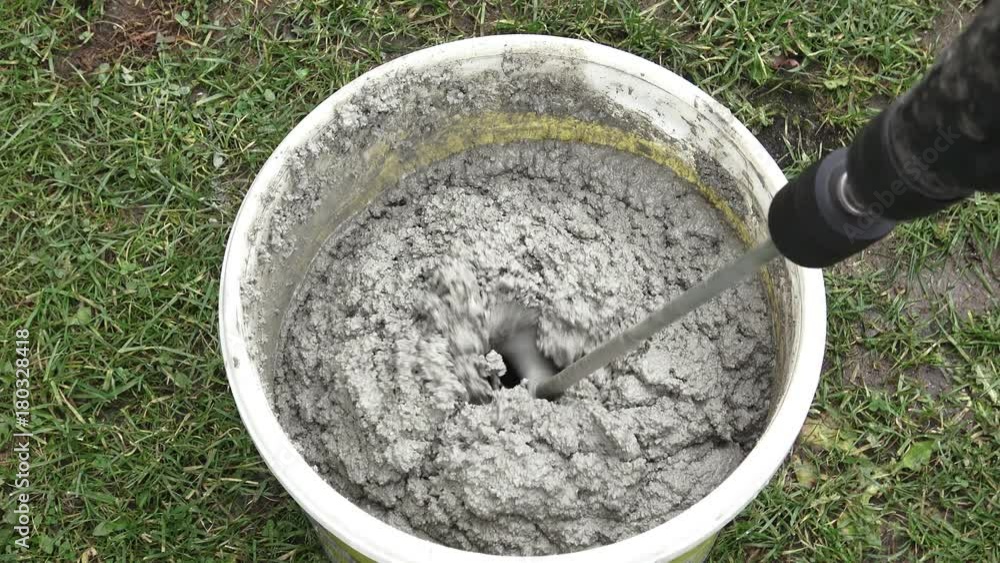 Builder mixing plaster in a bucket using an electric mixer. Mixing cement with a mixer in a bucket. Builder mixing plaster in a bucket using an electric mixer. Mixing cement with a mixer in a bucket.