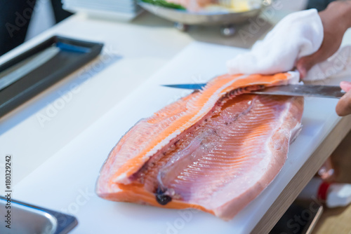 Japanese chef show preparing a fresh salmon with sharp knife on a cutting board  in restaurant.
close up hand of japanses sushi chef slice a fresh raw sashimislicing raw fish for salmon sushi. photo