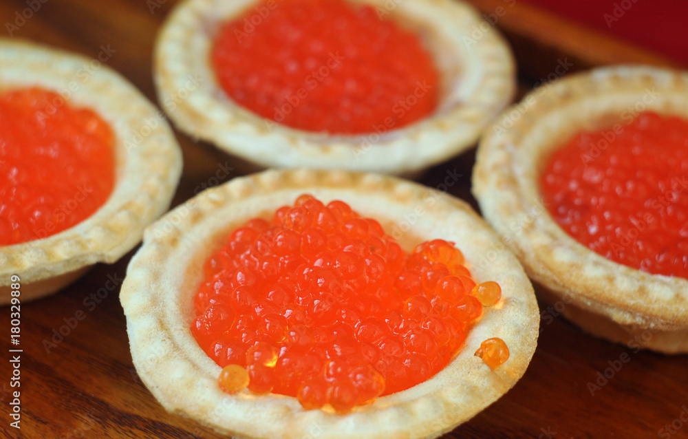 Tartlets with red caviar on a wooden plate. Tartlets with red caviar on a wooden plate.
