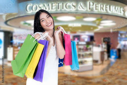 Beautiful Asian woman with shopping bags in duty free in International Airport before departure. Sale, shopping, tourism and happy people concept