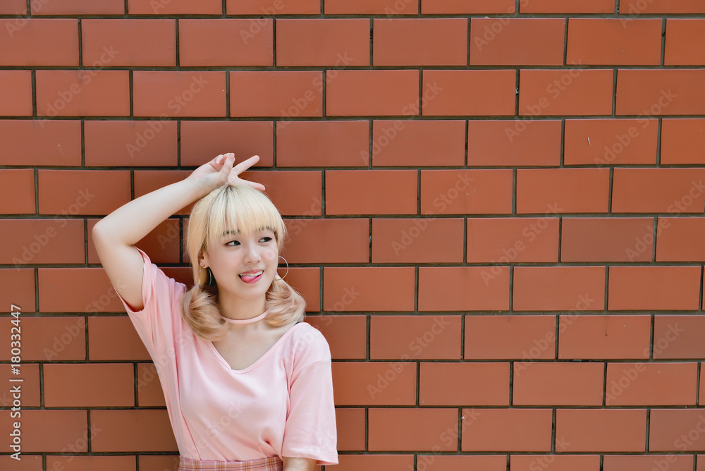 Portrait of thai woman golden hairs japan style on orange brick wall,Asian girl pose for take a picture outdoor Portrait of thai woman golden hairs japan style on orange brick wall,Asian girl pose for take a picture outdoor