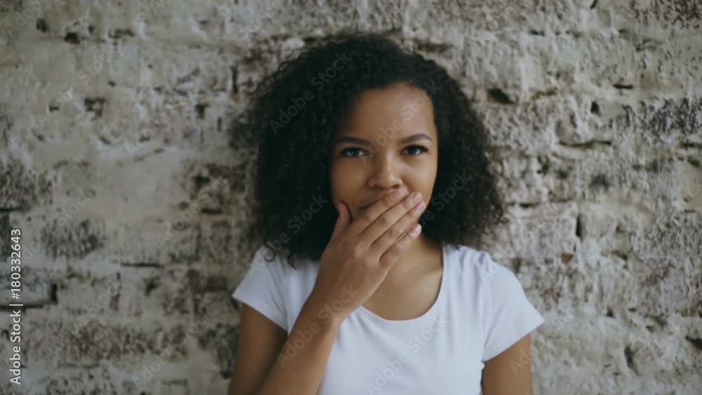 Portrait of curly mixed race woman actively surprising and wondering looking into camera on brick wall background Portrait of curly mixed race woman actively surprising and wondering looking into camera on brick wall background