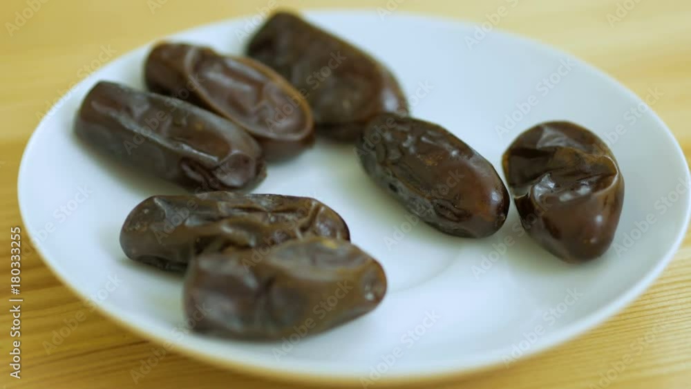 Hand taking dates fruit in the plate. People taking dates out of saucer.