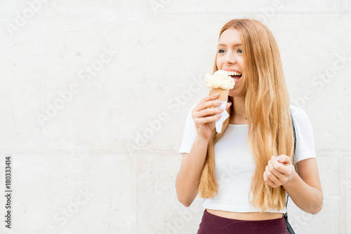 Vivacious redhead girl eating ice cream outdoors photo