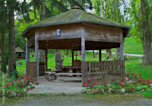 Open wooden hut with table and benches for relaxing in park