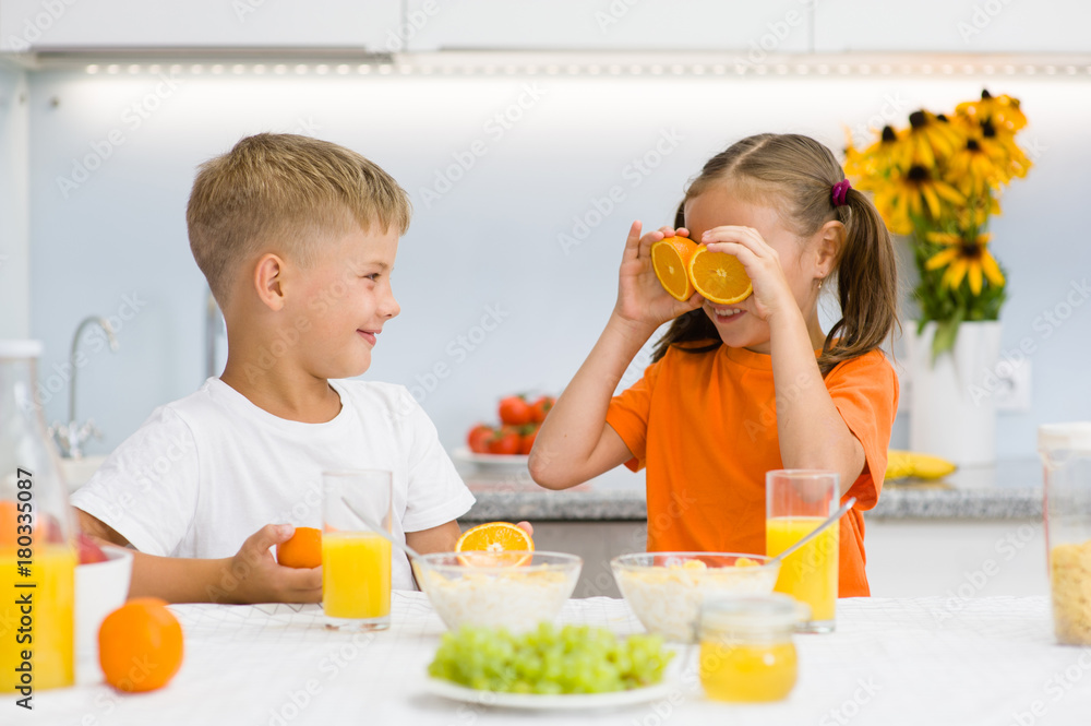 Brother laughs at his sister with orange before his eyes like in glasses Brother laughs at his sister with orange before his eyes like in glasses