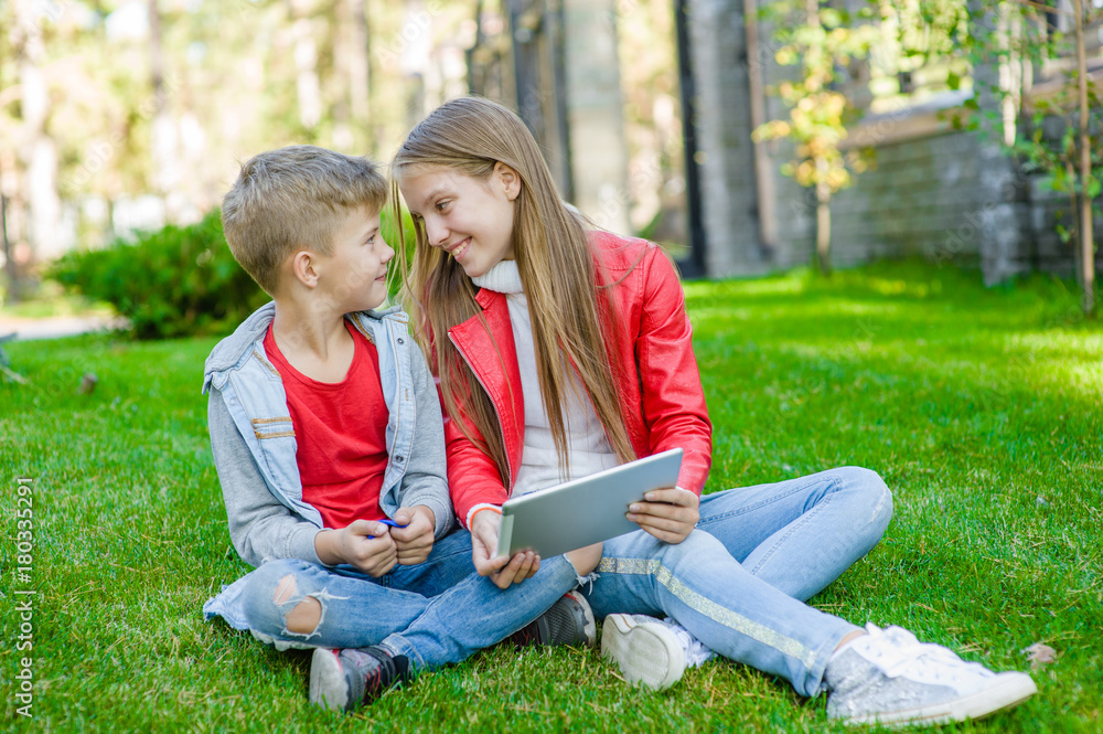 children enjoy the tablet computer in the open air
