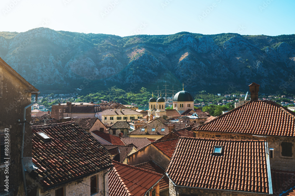 The view of red tile roofs in old town of Kotor with mountains on a background