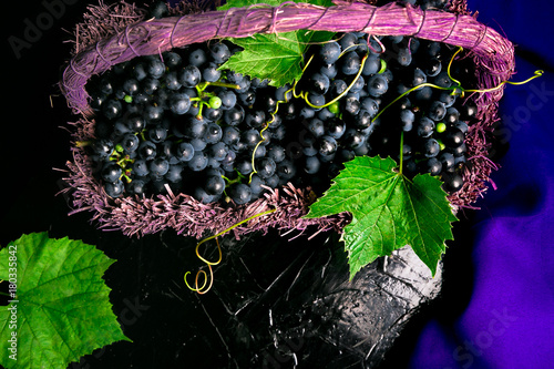 Red wine grapes in voiolet basket on bllack background. Top view. Copy space. photo