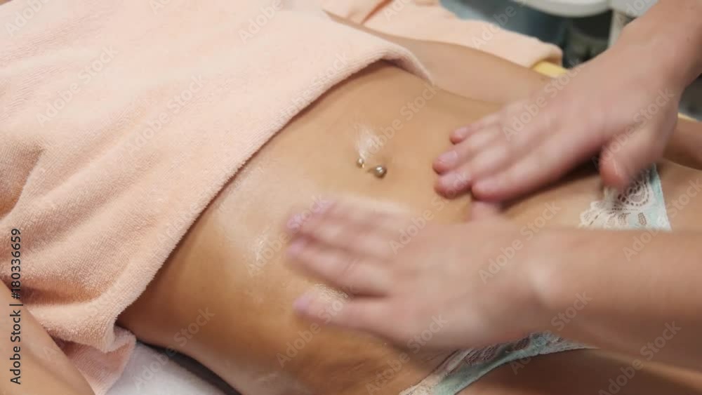 Brunette fit woman client receiving belly body massage at spa club by tattooed massagist. Brunette fit woman client receiving belly body massage at spa club by tattooed massagist.
