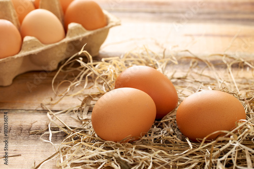 Fresh chicken eggs and straw on wooden background