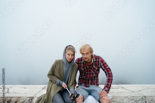 Young couple trying to make a selfie on bad weather surrounded by fog