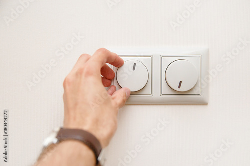 Saving energy concept: Human hand turning down electrical light dimmer switch or conditioner heat controller
