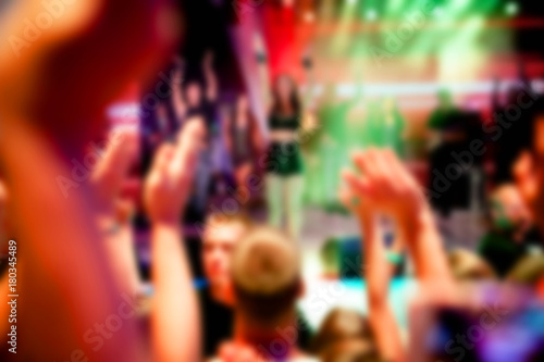 Blurred for background. Ibiza night club. Artist performs songs and dance show from stage during concert at nightclub. Artist on club stage during night party.