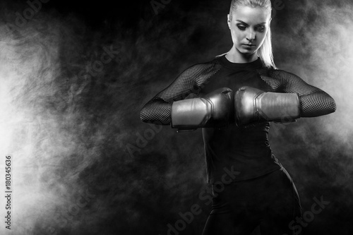 A strong athletic, woman boxer, boxing at training on the black background. Sport boxing Concept with copy space. © Mike Orlov