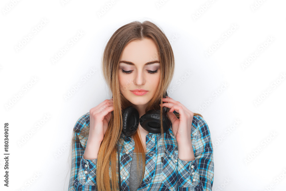 Headshot of a young adorable blonde woman in blue plaid shirt enjoying listening music to big professional dj headphones. Headshot of a young adorable blonde woman in blue plaid shirt enjoying listening music to big professional dj headphones.
