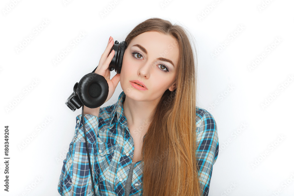 Headshot of a young adorable blonde woman in blue plaid shirt enjoying listening music to big professional dj headphones. Headshot of a young adorable blonde woman in blue plaid shirt enjoying listening music to big professional dj headphones.