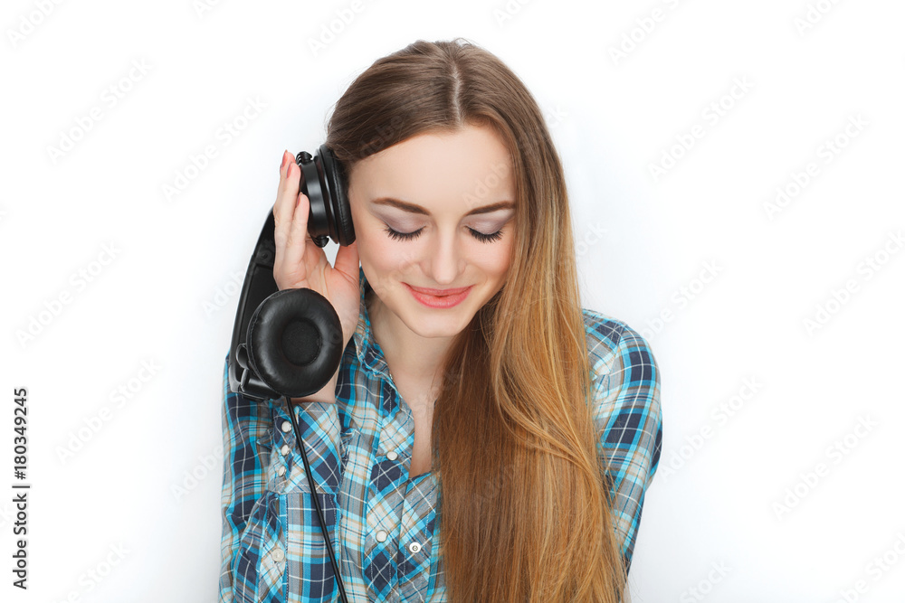 Headshot of a young adorable blonde woman in blue plaid shirt enjoying listening music to big professional dj headphones. Headshot of a young adorable blonde woman in blue plaid shirt enjoying listening music to big professional dj headphones.