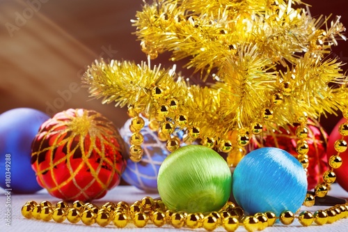 Golden christmas tree with decorated balls and light beams on dark background.
