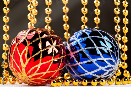 Christmas balls and golden garland with light beams on dark background.