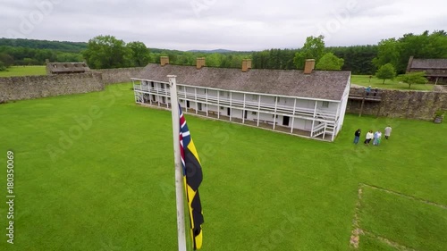 Aerial of the Calvert Arms/King’s Colors flag waving in the breeze with the barracks in the distance at Fort Frederick in Maryland. photo