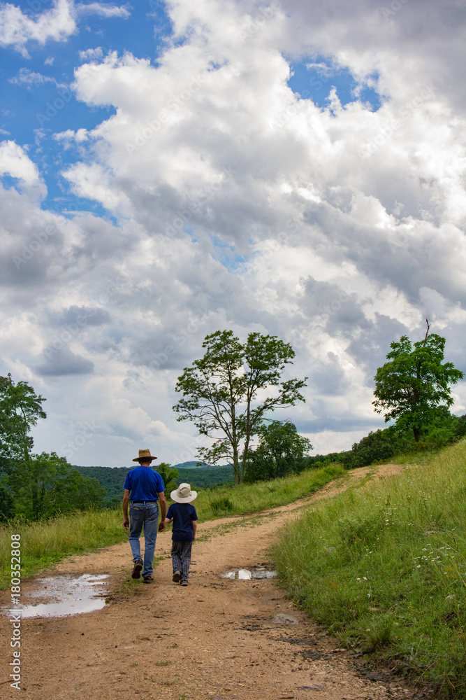 Man and boy walking up a dirt road .
