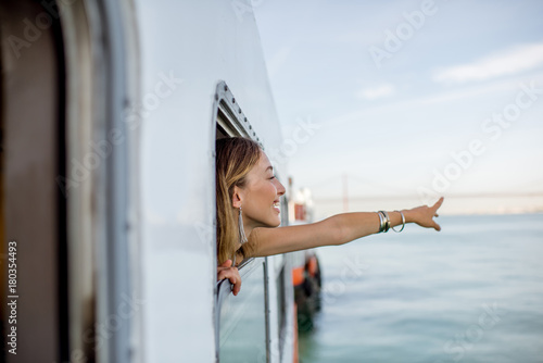 Young woman traveler pulling out face from the window in the water taxi in Lisbon, Portugal photo