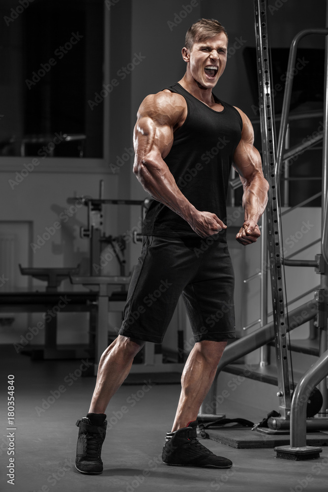 Fototapeta premium Sexy muscular man in gym, working out. Strong male showing muscles