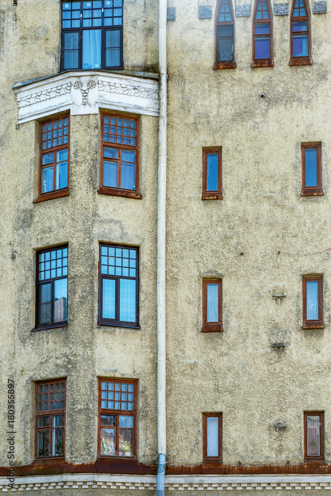 The wall of the house with windows of different sizes and shapes