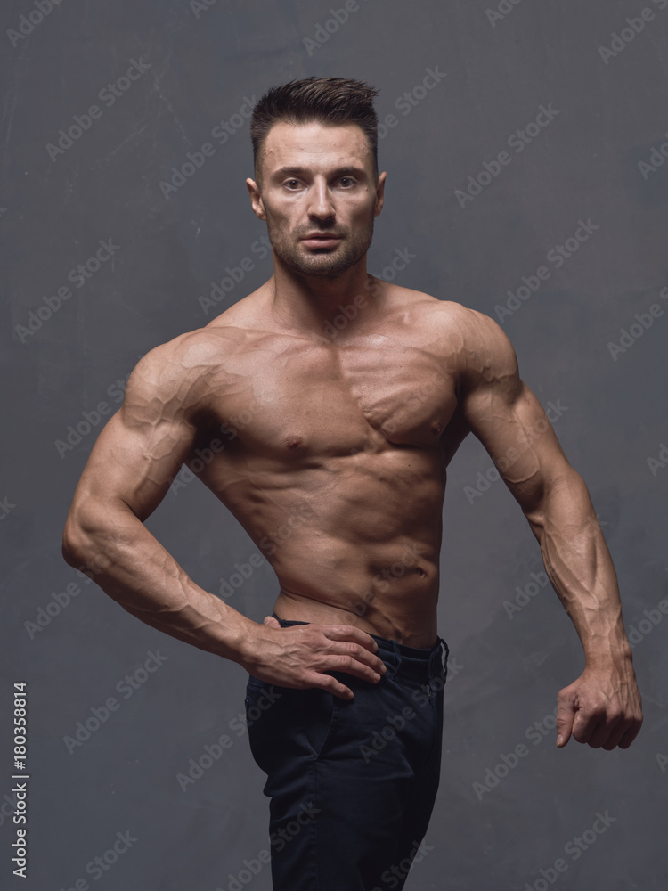A physically strong man in black trousers and a naked torso. A physically strong man in black trousers and a naked torso.