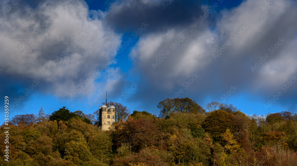 Folly on a hill top in Peak District, Derbyshire, England - stone tower in the forest on a bright autumn day