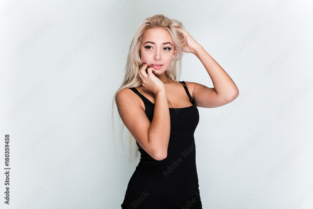 Perfect beauty. Beautiful young woman with blond hair looking away with smile while standing against grey background Perfect beauty. Beautiful young woman with blond hair looking away with smile while standing against grey background