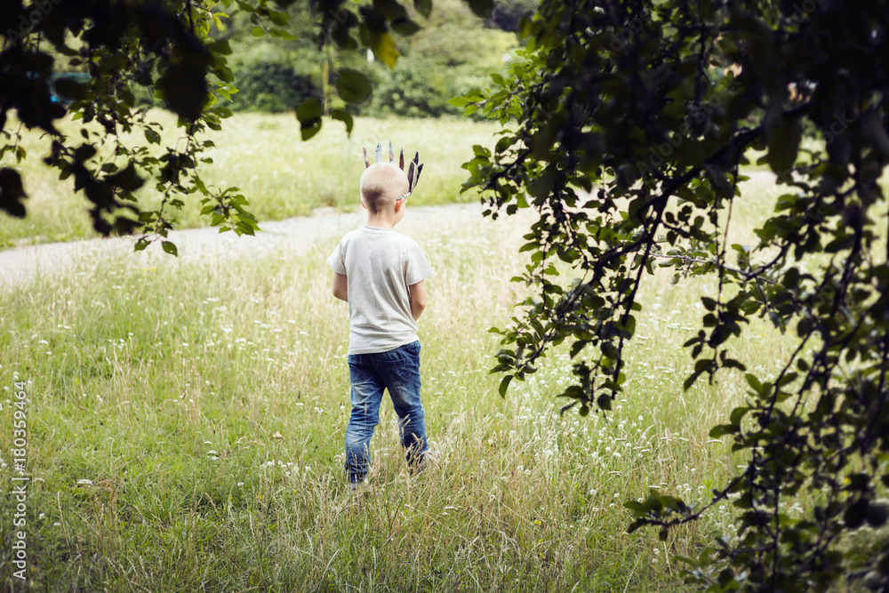 6-year-old boy walking throug a field wearing a paper crown. 6-year-old boy walking throug a field wearing a paper crown.