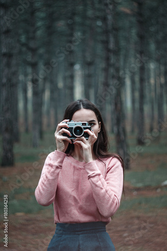Girl photographer in the woods holds in her hand an old vintage film camera photo