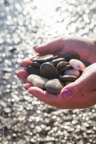 Sea stones in hands on the beach in the summer