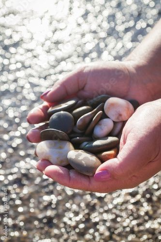 Sea stones in hands on the beach in the summer