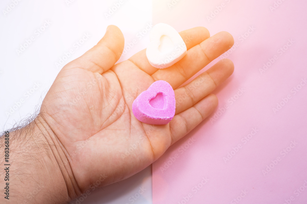 Hands holding two heart-shaped candies