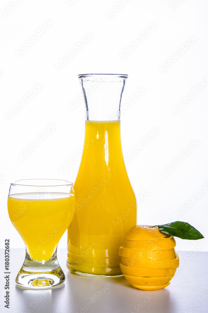 decanter, glass with orange juice, cut orange on a fresh table and a white background.