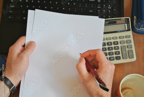 Kartka papieru trzymana w rękach mężczyzny ułożonych na biurku