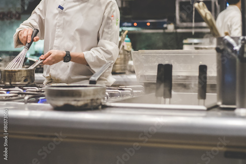 Closeup of Chef in restaurant kitchen at stove with pan.